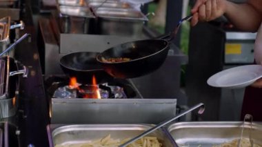 Şef gaz ocağının üstünde eski bir tavada yemek hazırlıyor.