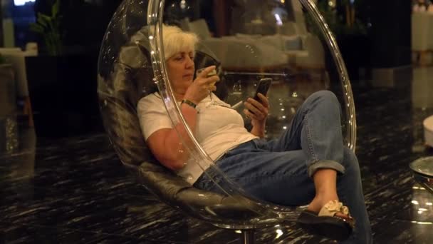 Γυναίκα απολαμβάνει ένα απεριτίφ κρασί χαλαρώνοντας σε μια μοντέρνα καρέκλα μπανιέρα — Αρχείο Βίντεο