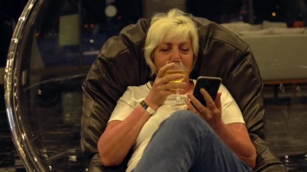 Женщина расслабляется с бокалом охлажденного белого вина — стоковое видео