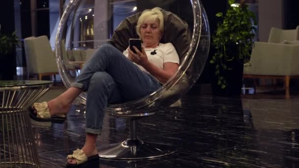 Laag uitzicht op een vrouw ontspannen in een hotel lobby of lounge — Stockvideo