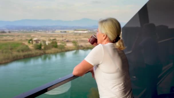 Женщина расслабляется за чашкой кофе на балконе отеля — стоковое видео