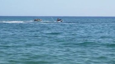 Jet ski ve sandal okyanusta bir yaz gününün tadını çıkarıyor.