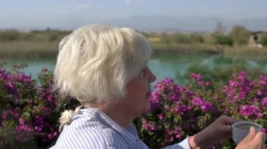 Sarışın kadın terasta kahve içiyor.