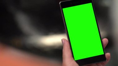 Elinde boş yeşil ekranlı akıllı bir telefon var.