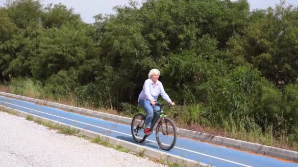 Fit healthy middle-aged woman riding a bicycle — Stock Video