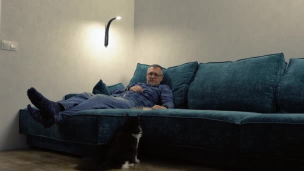 Homem de meia-idade desfrutando de uma noite relaxante com seu gato — Vídeo de Stock