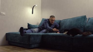 Orta yaşlı bir adam kedisine dokunmak için uzanıyor.