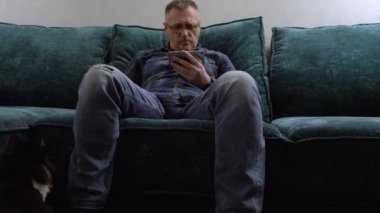 Rahat bir kanepede rahatlayan yırtık kotlu sıradan bir adam.