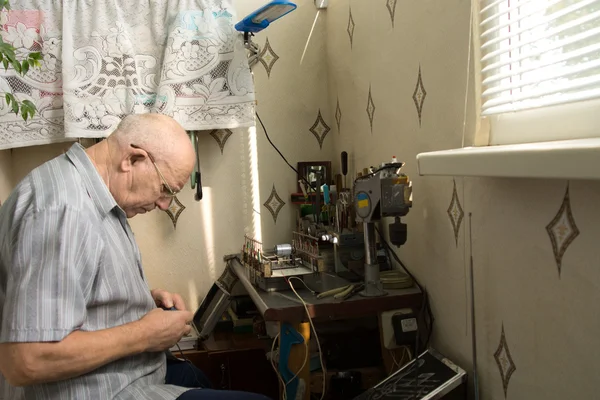 Zajęty stary człowiek wymyśla elektroniczny gadżet — Zdjęcie stockowe