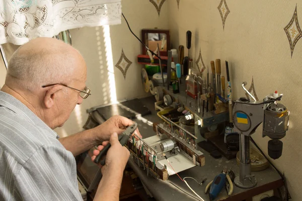Senior man working at a small work bench — Stock Photo, Image