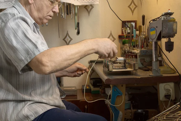 Oude man die werkt elektronisch apparaat op kleine tafel — Stockfoto