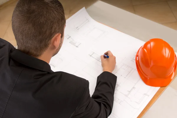 Young architect modifying a building plan — Stock Photo, Image