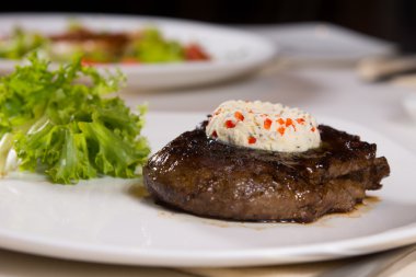 plaka üzerinde otlu tereyağı ile tepesinde biftek