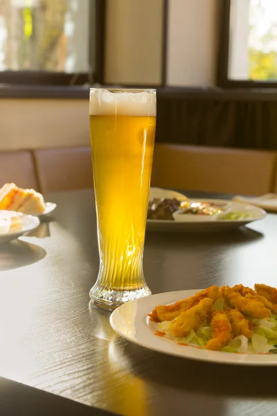 Tall Glass of Beer on Restaurant Table with Food — Stock Photo, Image