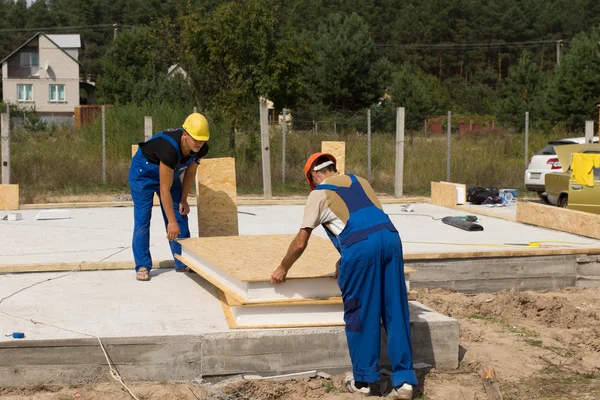 Dois construtores que manipulam painéis de parede isolados — Fotografia de Stock