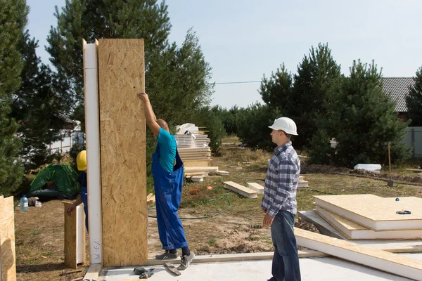 Construtores que erguem painéis de parede isolados — Fotografia de Stock