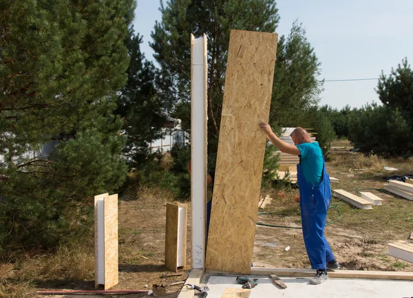 Trabalhador que ergue painéis de parede em um canteiro de obras — Fotografia de Stock