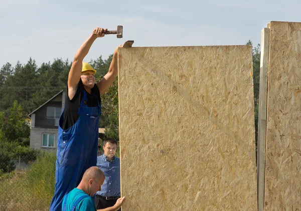 Carpinteros erigiendo paneles de pared en una nueva construcción — Foto de Stock