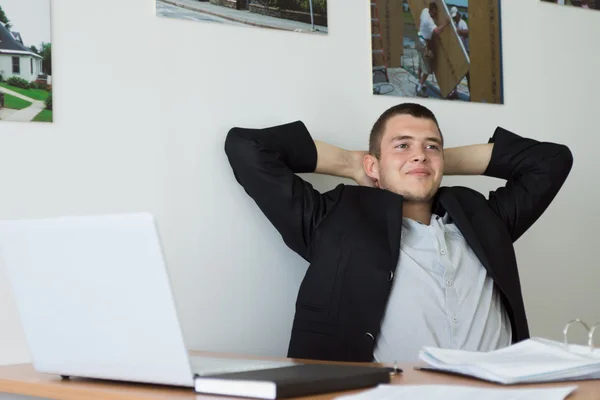 Sorridente giovane esecutivo Rilassarsi nella sua area di lavoro — Foto Stock