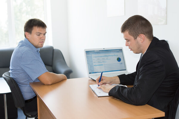 Серьезные бизнесмены за деревянным столом с компьютером
