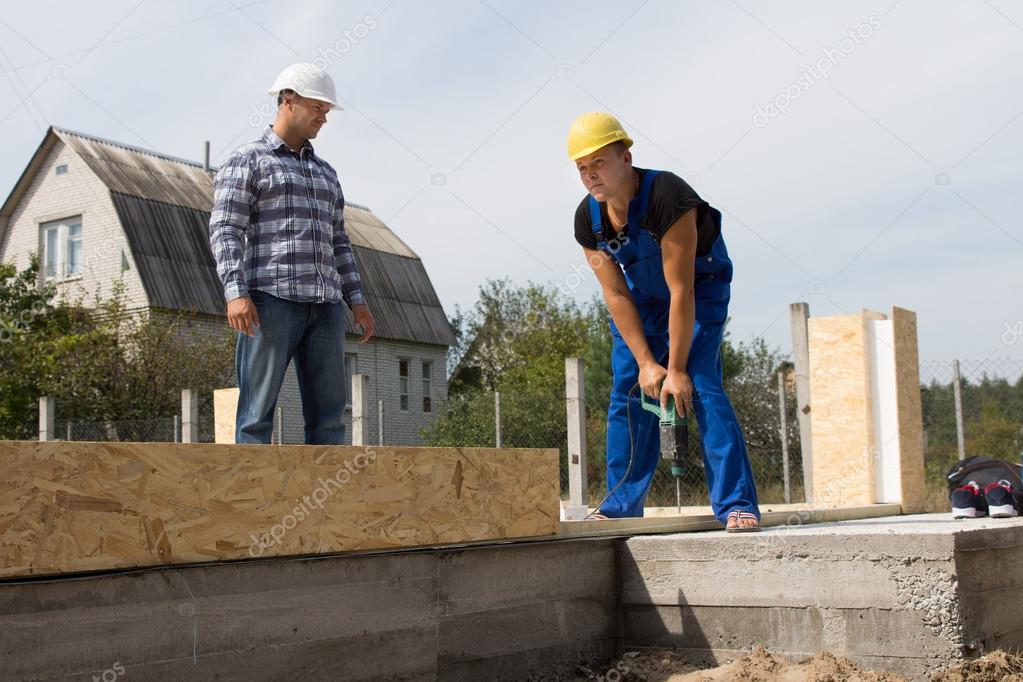 Engineer Looking at Construction Worker Drilling ??? Stock Photo