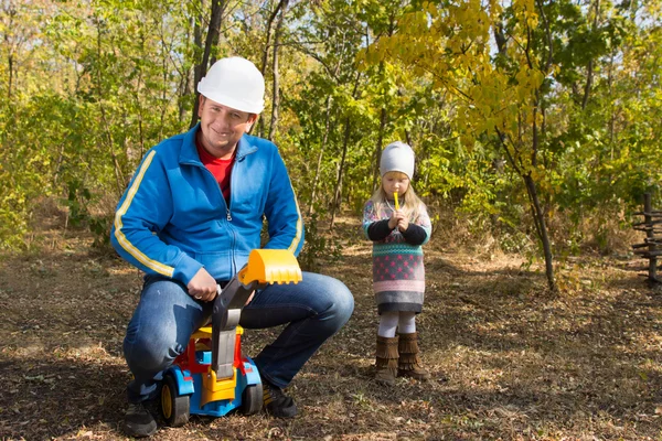 Father riding on his childs toy truck — Stock Photo, Image