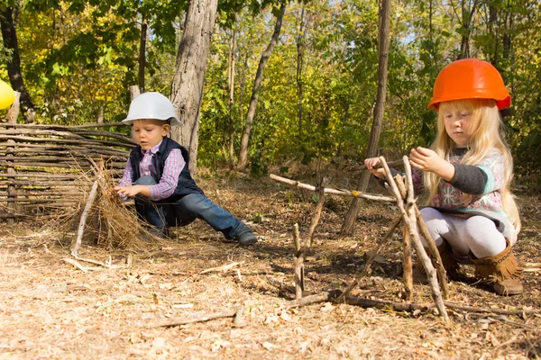 Twee jonge kinderen voorwenden om bouwers — Stockfoto