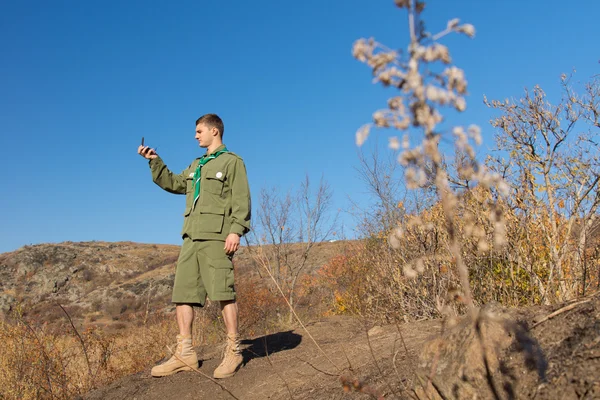 Bir pusula okuma alarak bir kaya üzerinde duran scout — Stok fotoğraf