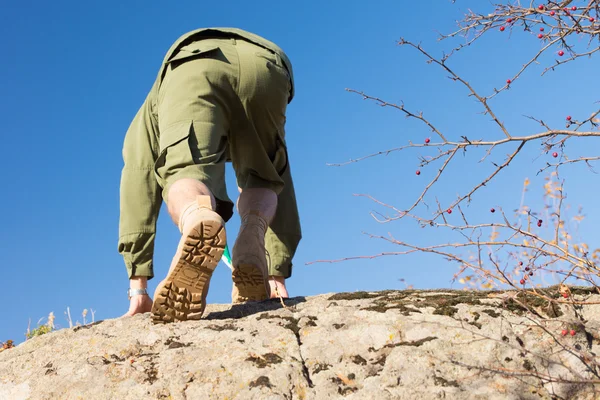 Escoteiro de uniforme escalando uma rocha grande — Fotografia de Stock