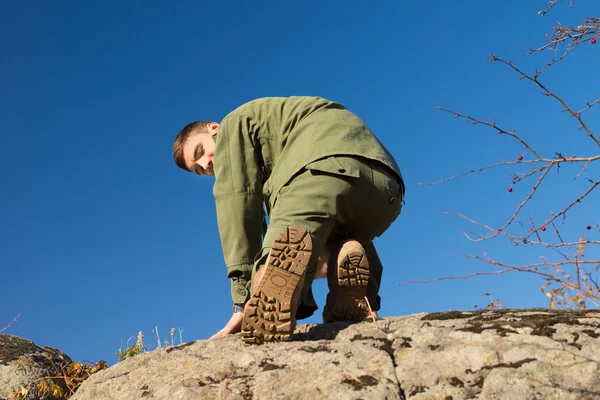 Niños explorador escalando en la roca mientras mira su espalda — Foto de Stock