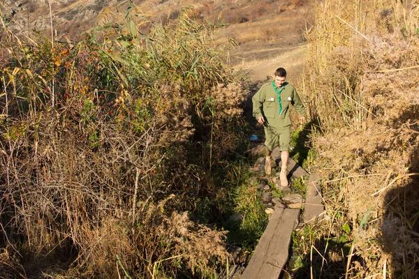 Scout che attraversa uno stretto ponte pedonale su un ruscello — Foto Stock