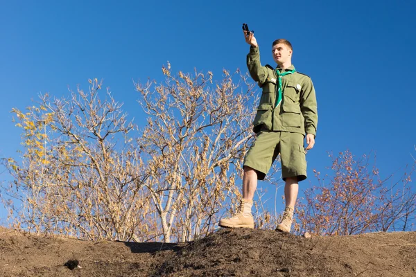Scout standing on a rock taking a compass reading — Stock Photo, Image