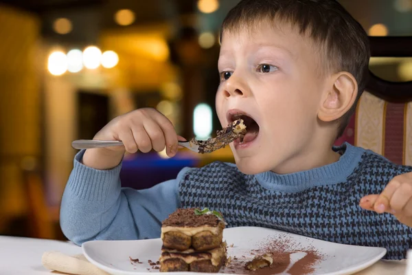 Menino comendo uma grande boca cheia de bolo — Fotografia de Stock