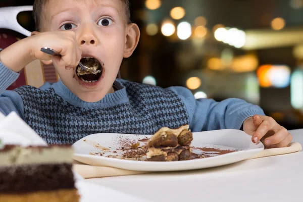 Petit garçon affamé avalant une tranche de gâteau — Photo