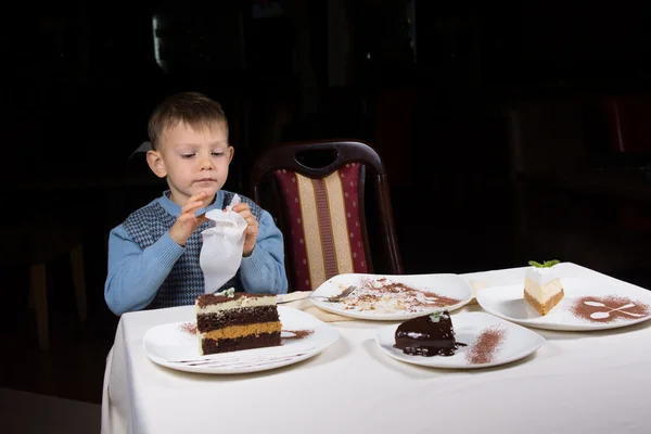 Liten pojke avslutar en bit av kakan vid bord — Stockfoto