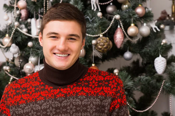 Handsome young man in front of a Xmas tree — Stock Photo, Image