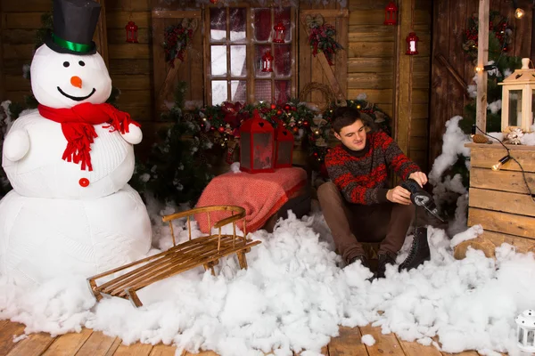 Hombre sentado en una decoración de nieve de algodón sosteniendo patines — Foto de Stock