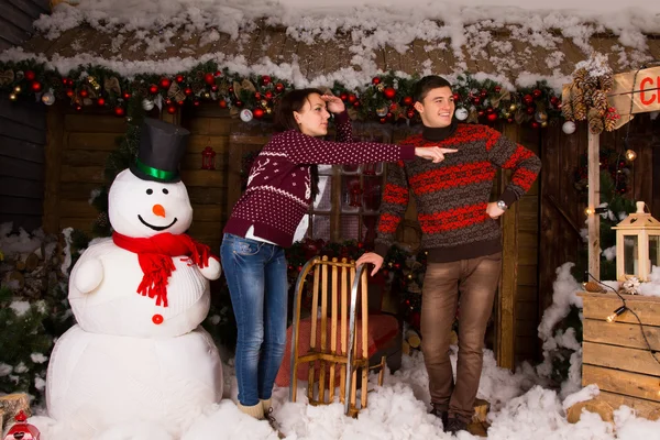 Casal perto de boneco de neve interior olhando para o quadro certo — Fotografia de Stock