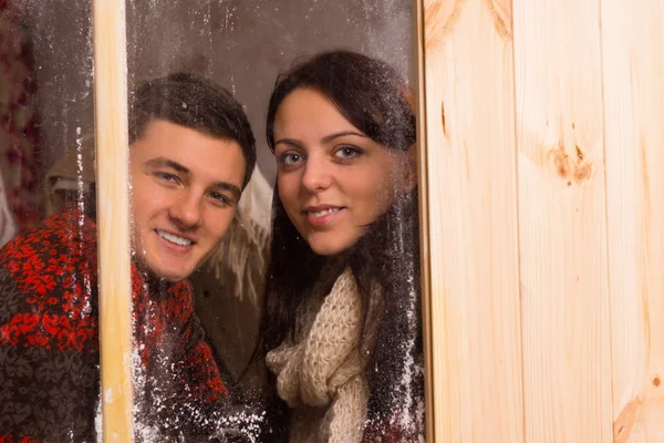 Sorrindo jovem casal olhando através de uma janela — Fotografia de Stock