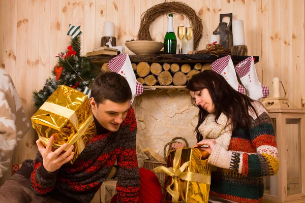 Ung man och kvinna öppnar sina Xmas gåvor — Stockfoto