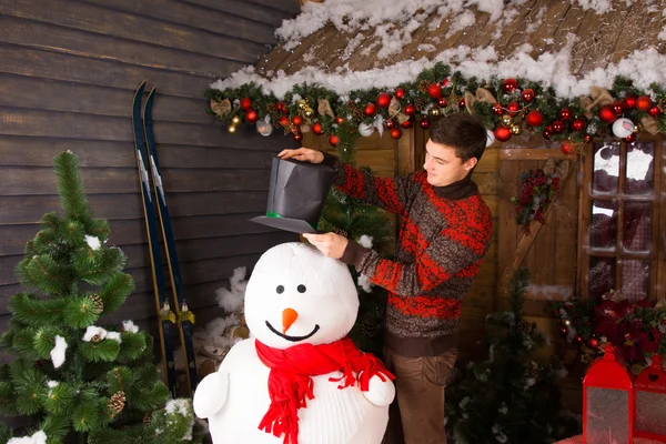 Jovem colocando chapéu preto no interior boneco de neve — Fotografia de Stock