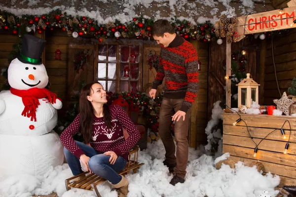 Casal com trenó ao ar livre no inverno no Log Cabin — Fotografia de Stock