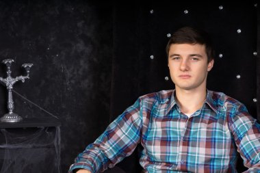 Peluş siyah yüksek geri sandalye oturan genç adam
