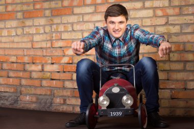 Young Man Riding on Vintage Toy Car clipart