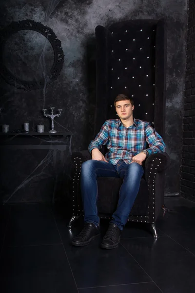 Человек, сидящий на высоком спинном стуле в жутком положении — стоковое фото
