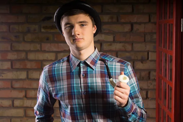 Молодой человек в клетчатой рубашке держит курительную трубу — стоковое фото