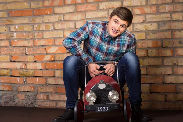 Young man having fun riding a toy truck — Stock Photo, Image