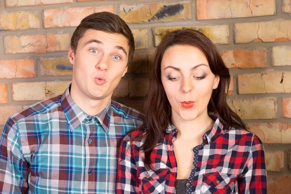 Young Couple Puckering Lips in front of Brick Wall — Stock Photo, Image