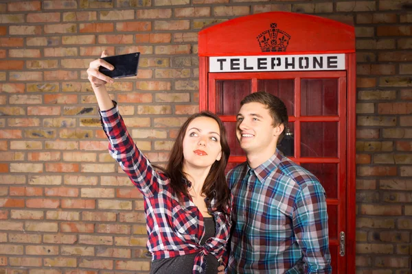 Пара, делающая автопортрет с красной будкой телефона — стоковое фото