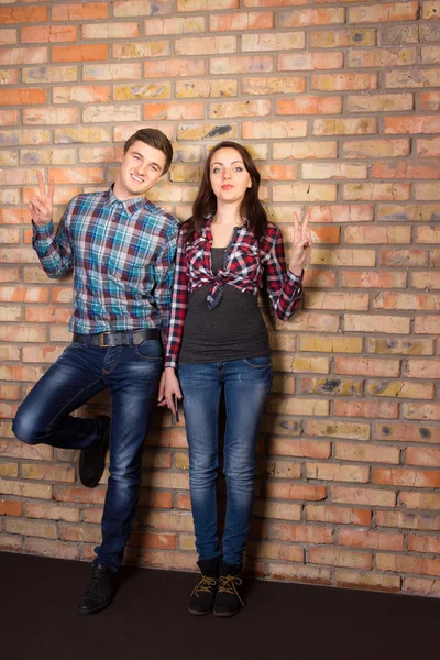 Jovem casal branco posando na parede de tijolo — Fotografia de Stock